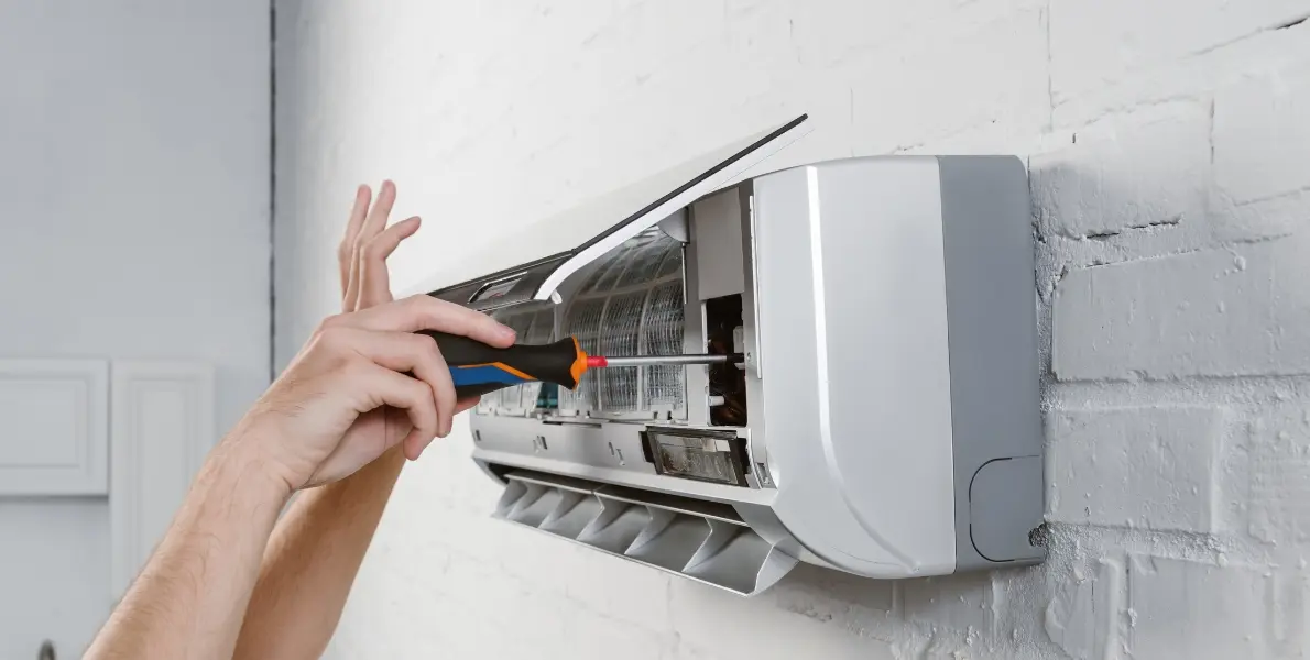 Technician repairing a wall-mounted AC unit in Dubai apartment